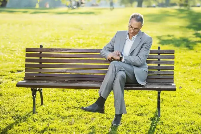A person doing a deep breathing exercise on a park bench surrounded by trees in morning mist